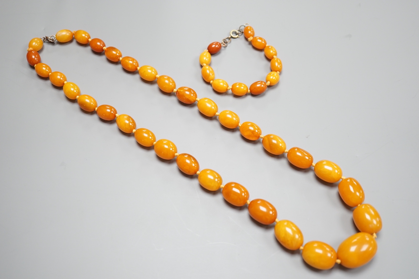 A single strand graduated oval amber bead necklace, 65cm and a similar bracelet, 18cm, gross weight 82 grams.